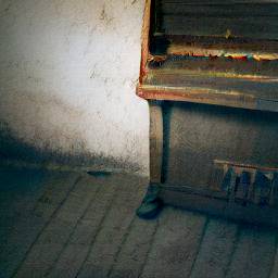 Photo of a smallish old piano in a house's living room with small fluffy clouds floating over it